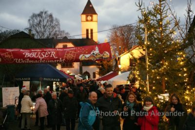 zu sehen ist der Eingangsbereich des Weihnachtsmarktes mit vielen Menschen und bunten Lichtern