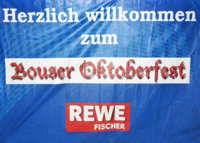 zu sehen ist ein Banner mit dem Aufdruck Herzlich Willkommen zum Bouser Oktoberfest wuenscht REWE Fischer
