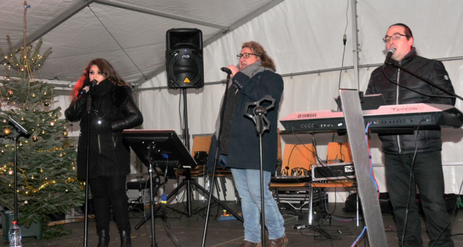 zu sehen sind zwei Musiker und eine Saengerin bei der Live Musik am Bouser Weihnachtsmarkt